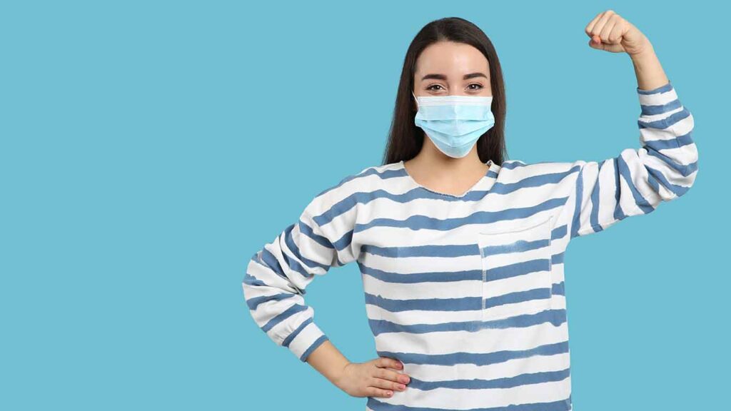 Woman with protective mask showing muscles on light blue backgro